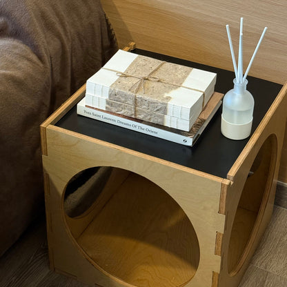 Wooden side table with books and a diffuser on a wooden floor.
