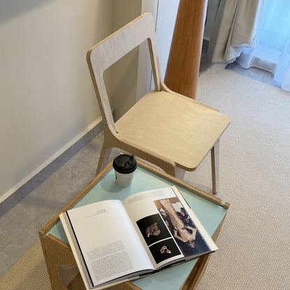 Small wooden table with an open book and a cup on a light-colored floor.