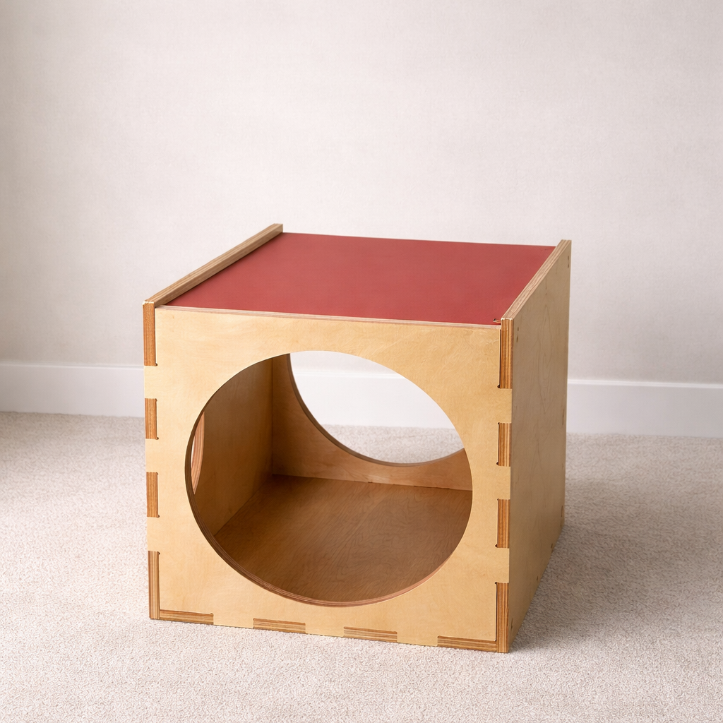 Wooden cube with a red top on a light gray floor.